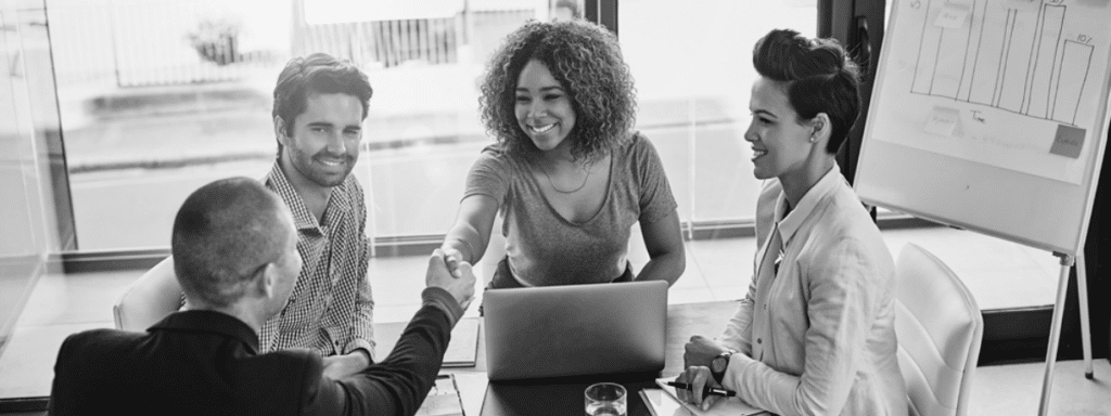 4 people smiling while meeting, shaking hands